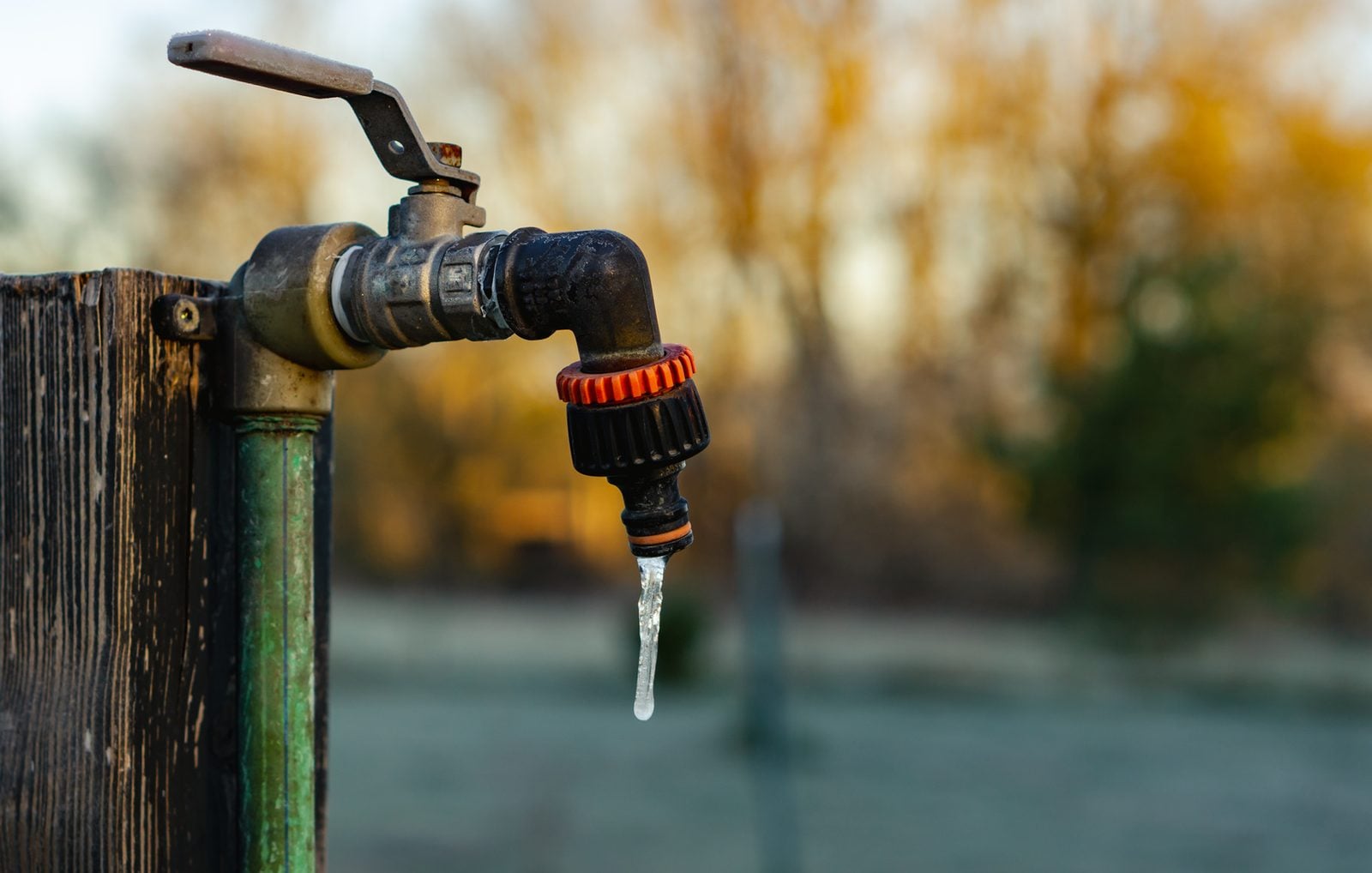 Outdoor garden faucet with a frozen icicle in winter